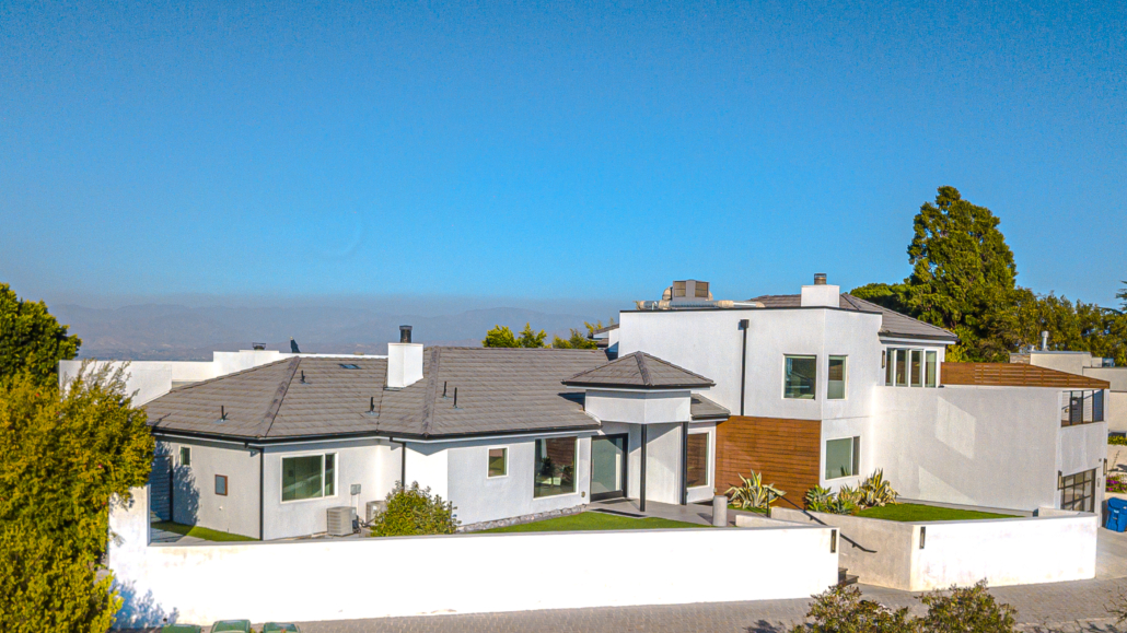 White residence with a broad roofline, landscaping and surrounding grounds